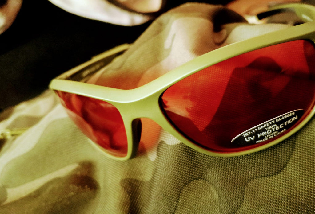 Close-up of Da One Sunset Olive Green sunglass frames red lenses with UV protection sticker